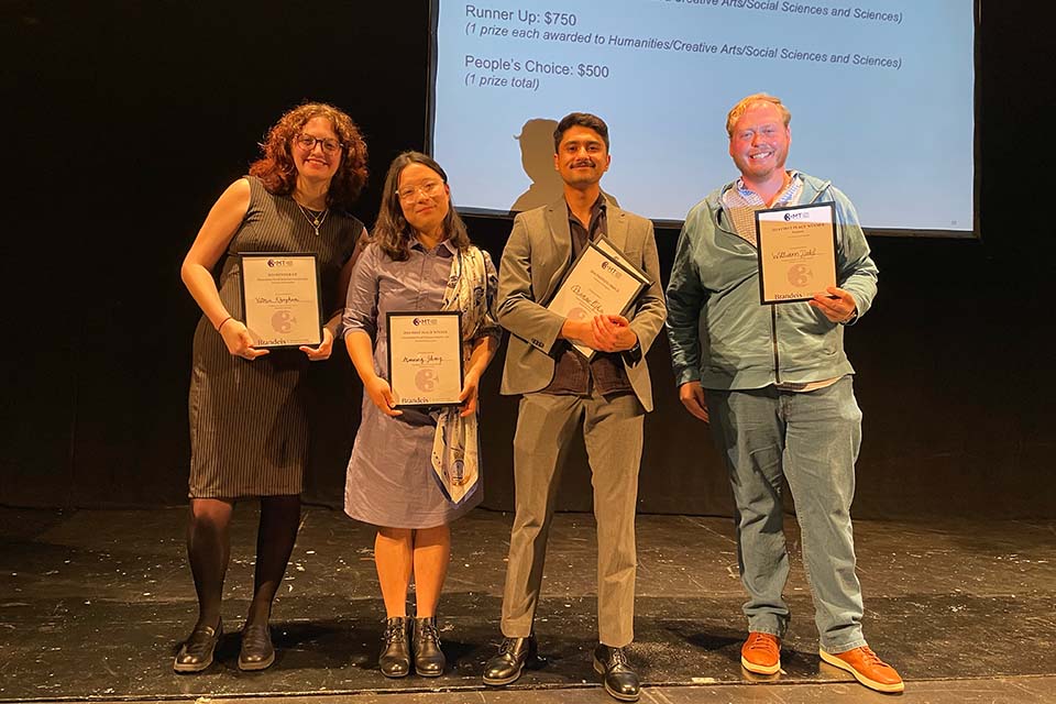 Victoria Khaghani, Manning Zhang, Pranav Ojha, and William Dahl pose onstage with their Three Minute Thesis prize certificates.