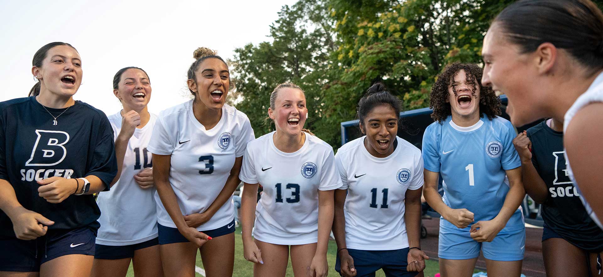 A group of soccer players gather in a group cheer