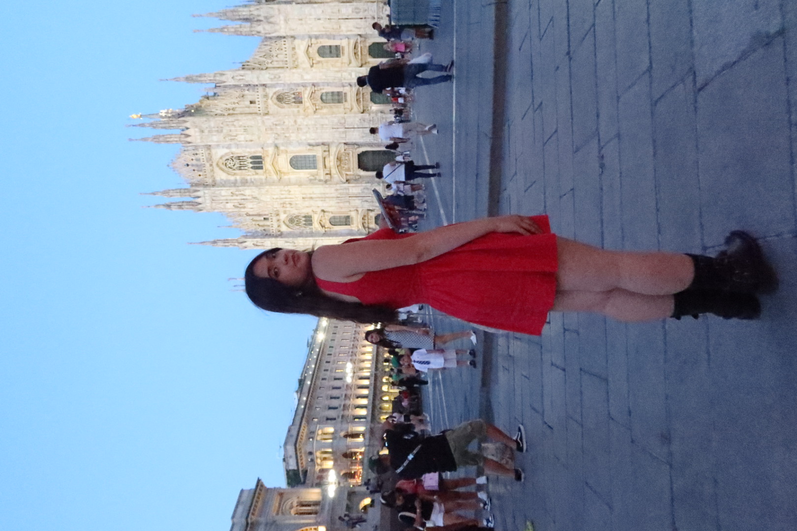 Karissa looks over her shoulder standing in front of a building in Italy at dusk.