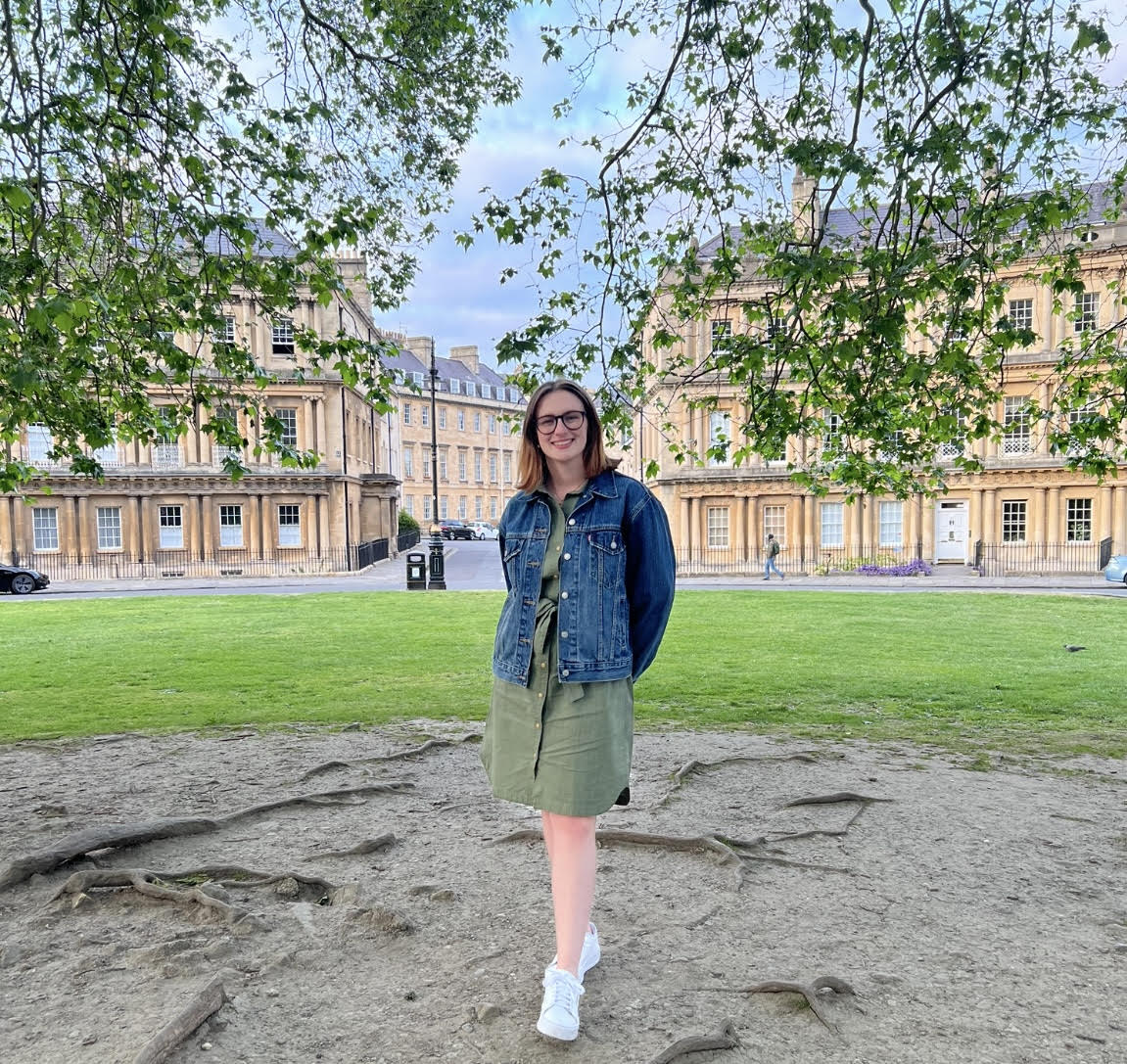 Laurel stands smiling in front of historic buildings in Bath city center on a sunny day.