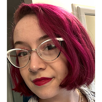 A white female with red hair wearing glasses and a stripped shirt