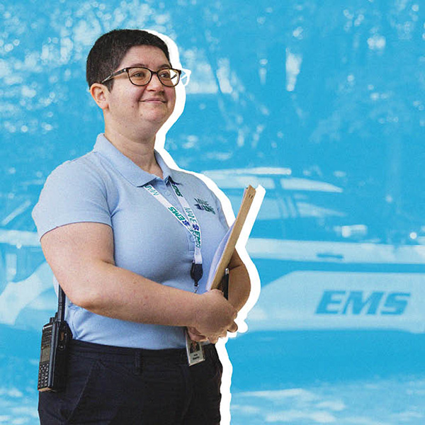 A woman holding a clipboard stands in front of an EMS vehicle.