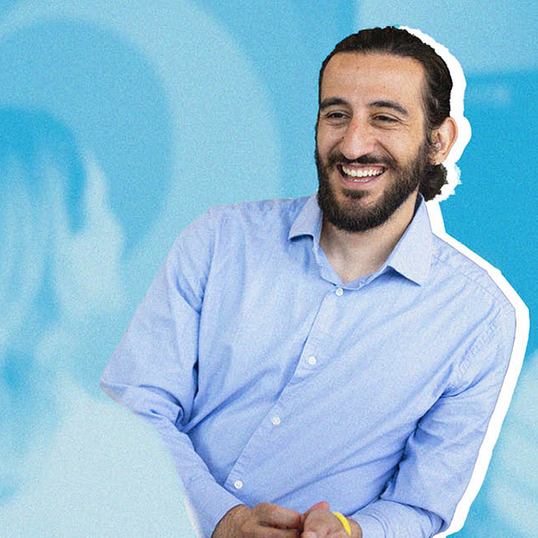 A man smiles against a blue background