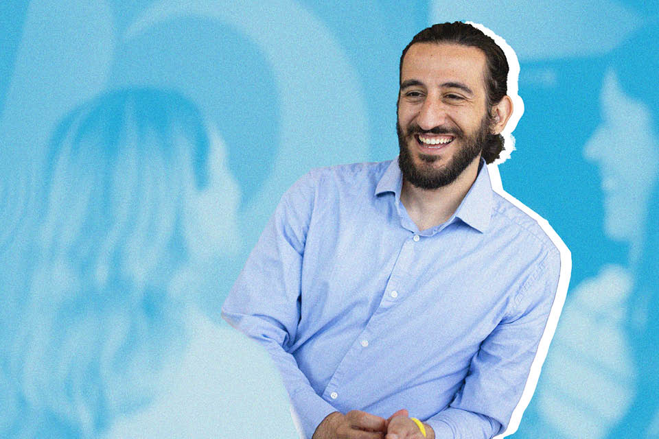 A man smiles against a blue background.