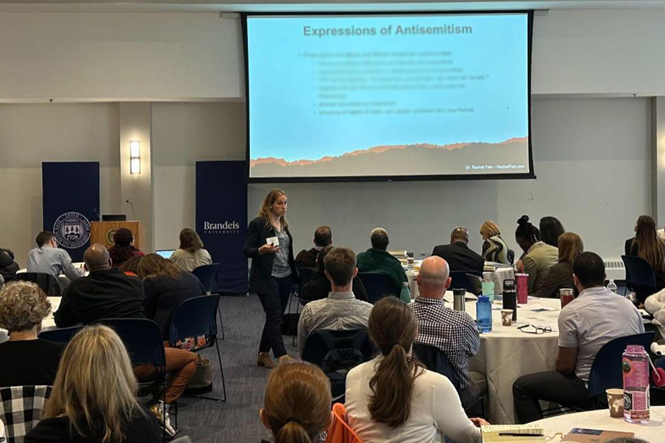 Dr. Rachel Fish teaching with slide titled "Expressions of Antisemitism" in background