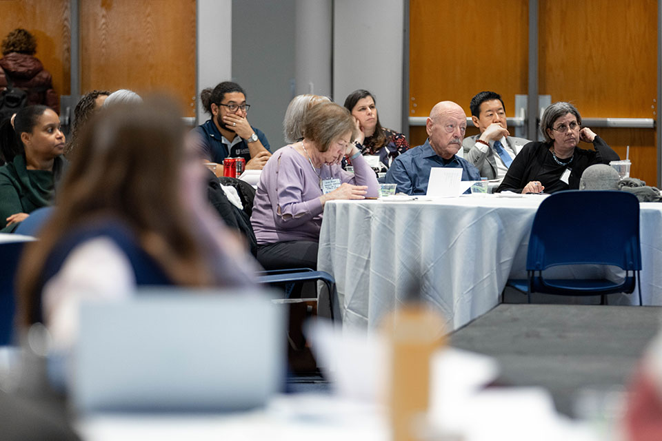 audience members sitting at tables listening intently