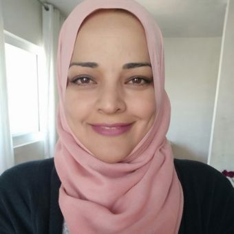 Laila wears a pink hijab and black blouse