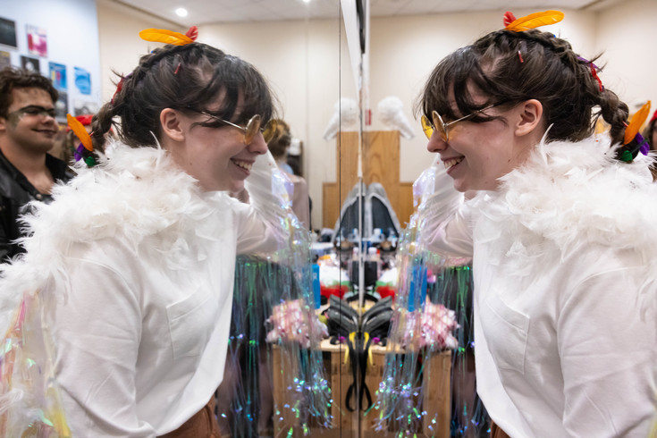 a student in costume smiles at her reflection 