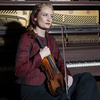 Clara has long blonde hair and holds a violin.