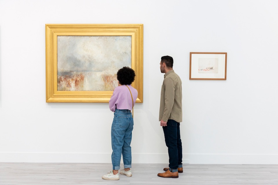 two people looking at a gold-framed Impressionist painting on a museum wall