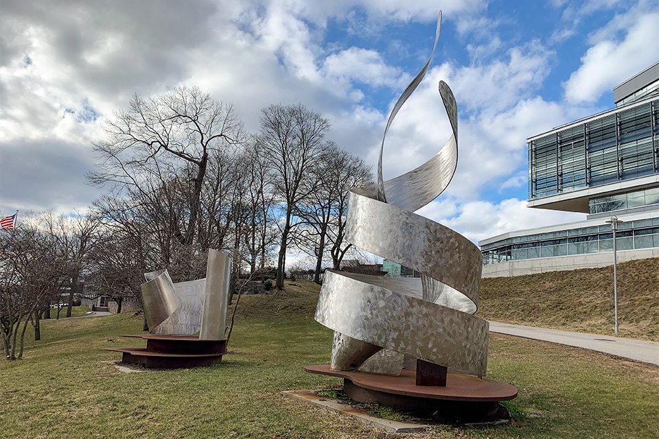 Wand of inquiry sculpture on campus, with the Shapiro Science Center in the background