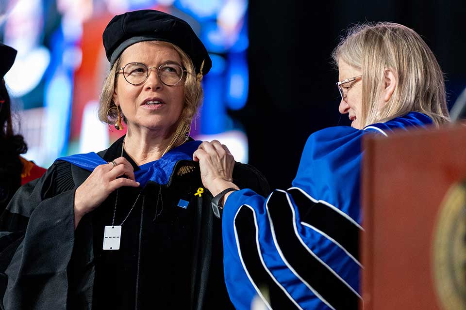Carol Fierke, on right, adjusts the academic hood worn by Ruth Halperin-Kaddari