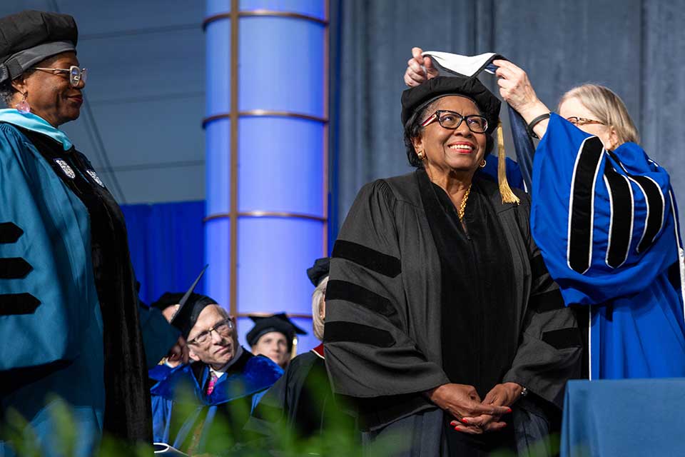 Ruth Simmons smiles as the academic hood is placed over her head