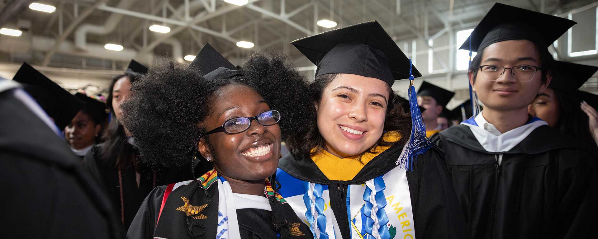 Graduates in caps and gowns smile at the camera during the 2024 Undergraduate Commencement ceremony