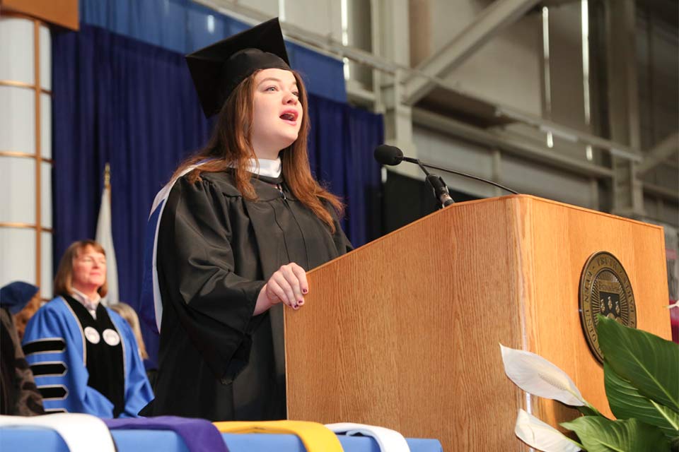 Morissa Ariel Pepose stands at a podium wearing a cap and gown