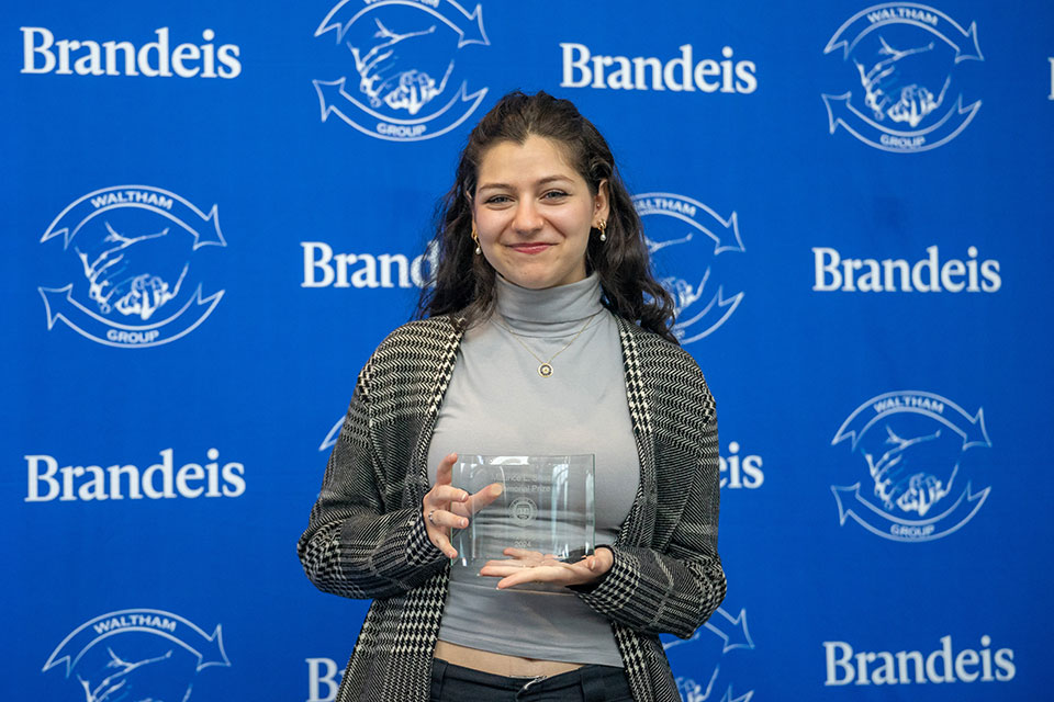 A student smiles for a photo and holds an award