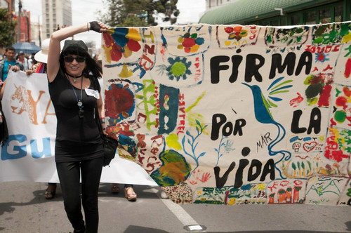 Woman holding a colorful sign that says "Firma por la vida" 