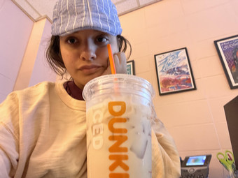 Aamna pictured wearing a hat and having a Dunkin drink