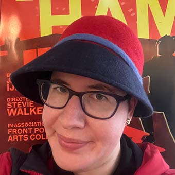 Abigail Arnold, standing in front of a poster for the play "Fat Ham"