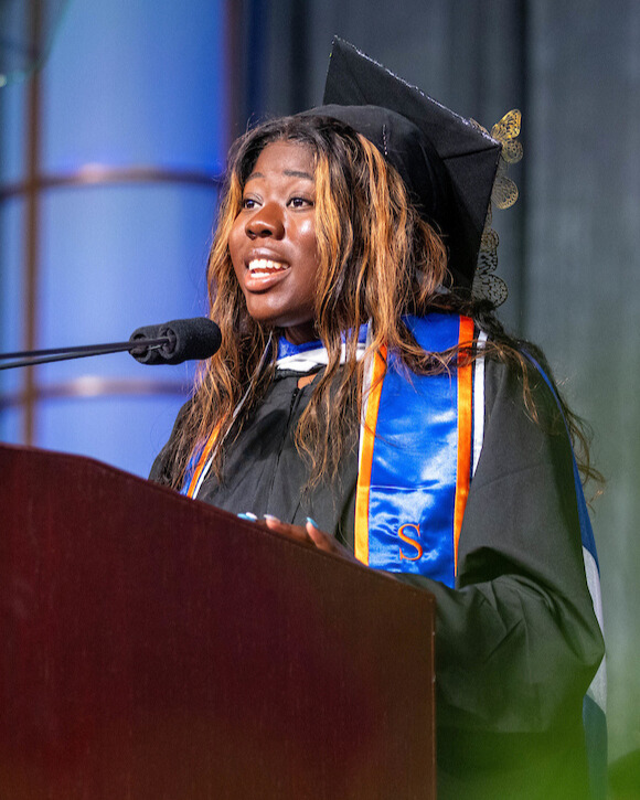 Brandeis graduate in cap and gown.