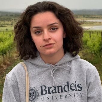 dark-haired person in a Brandeis sweatshirt, outdoors