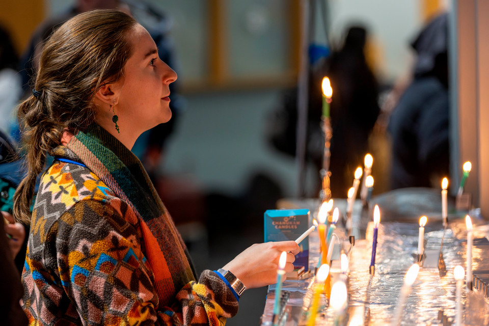 Student lights a menorah at a Chanukah event on campus