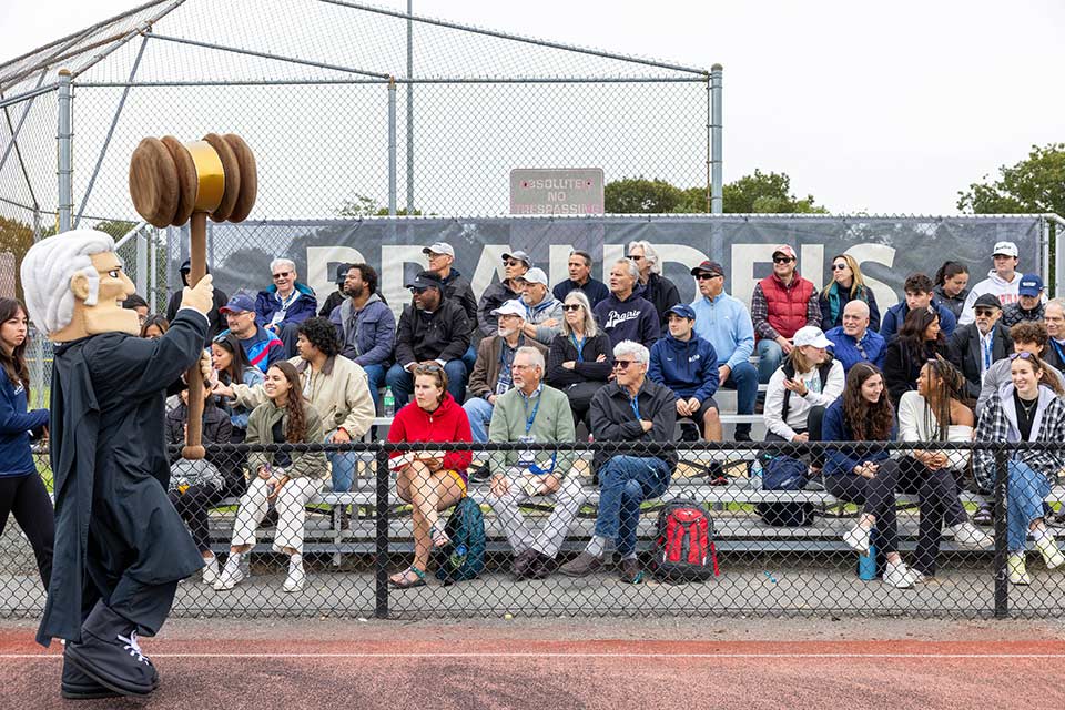 Group of people cheering at homecoming. The Judge mascot is also pictured.