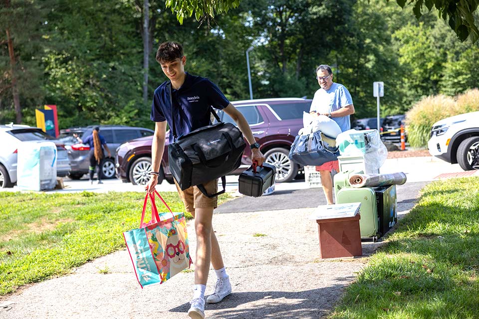 Two people carrying items across campus