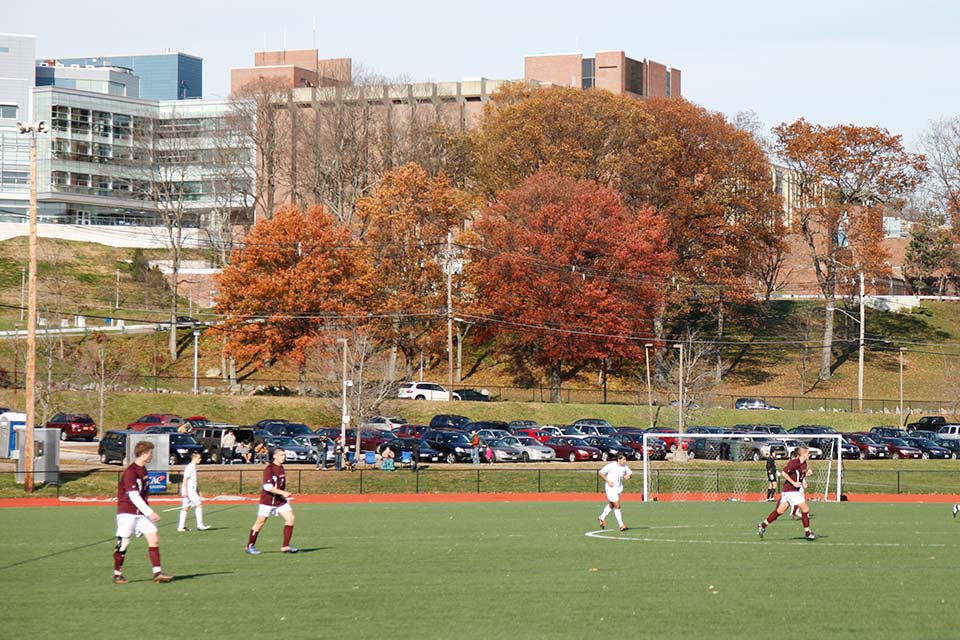 Soccer players on the field with the Brandeis campus in the background