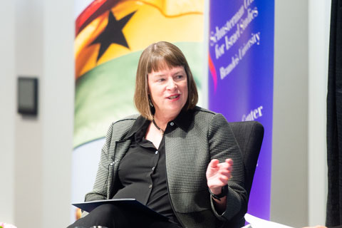 Auburn-haired woman in a black blouse and grey blazer gestures as she speaks to a listener not seen in the photo.