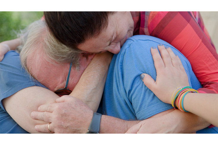 Scene from film "Holding Liat" shows people holding one another and crying