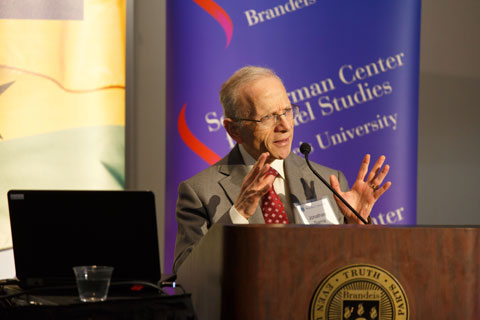 Jonathan Sarna at a podium, speaking, with the Schusterman Center for Israel Studies banner and the Brandeis International Business School banner behind him, in full color. 