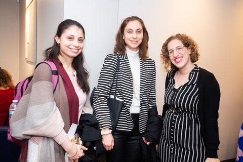 Three women - two doctoral fellows and a conference speaker, smile and face the camera. 