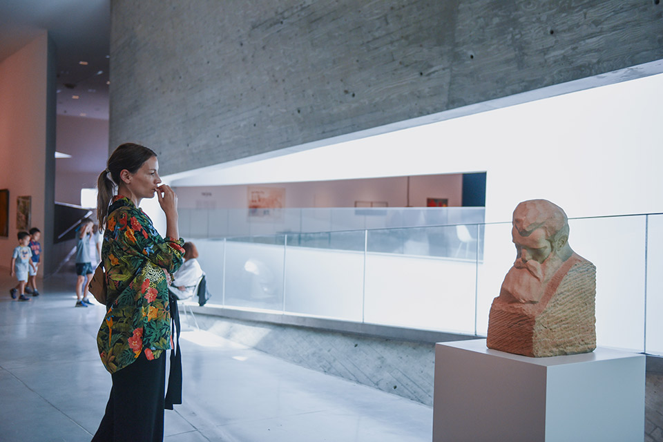 Woman contemplates bust of Herzl indoors