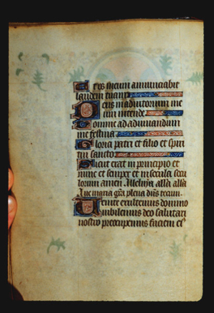 Page of blackletter text with several decorated initial letters and numerous other ornaments and decorative elements. The painting on the reverse side is faintly visibld through the page.