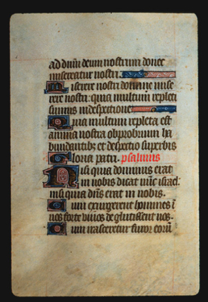 Page 53v, containing a dense block of blackletter text, with 6 illuminated initial letters,  one red word and two horizontal ornamental elements that fill the space from the end of a sentence to the right margin. 