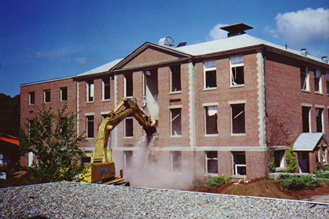 Picture of a crane in the beginning stages of demolishing the building.