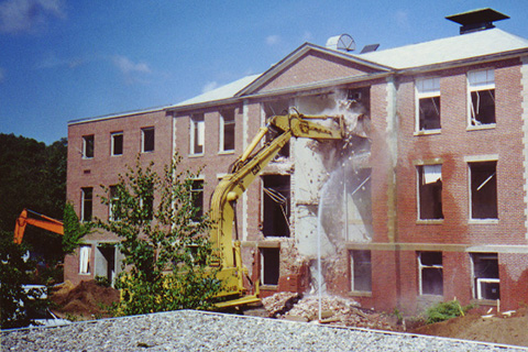 Crane tearing down the front facade of Ford Hall while hoses spray water.