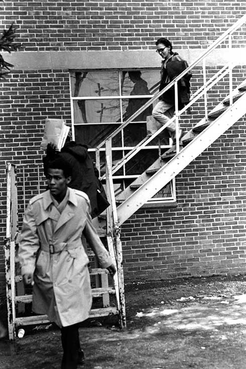 Three people walking down a set of stairs outside of a building.