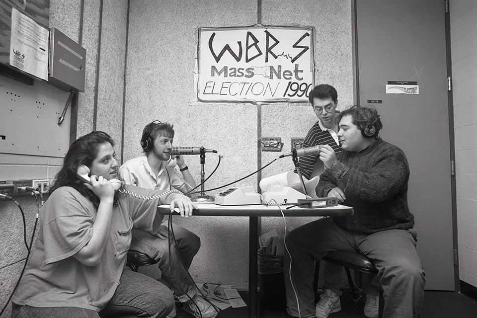 Black and white photo of four people inside WBRS radio station in 1990