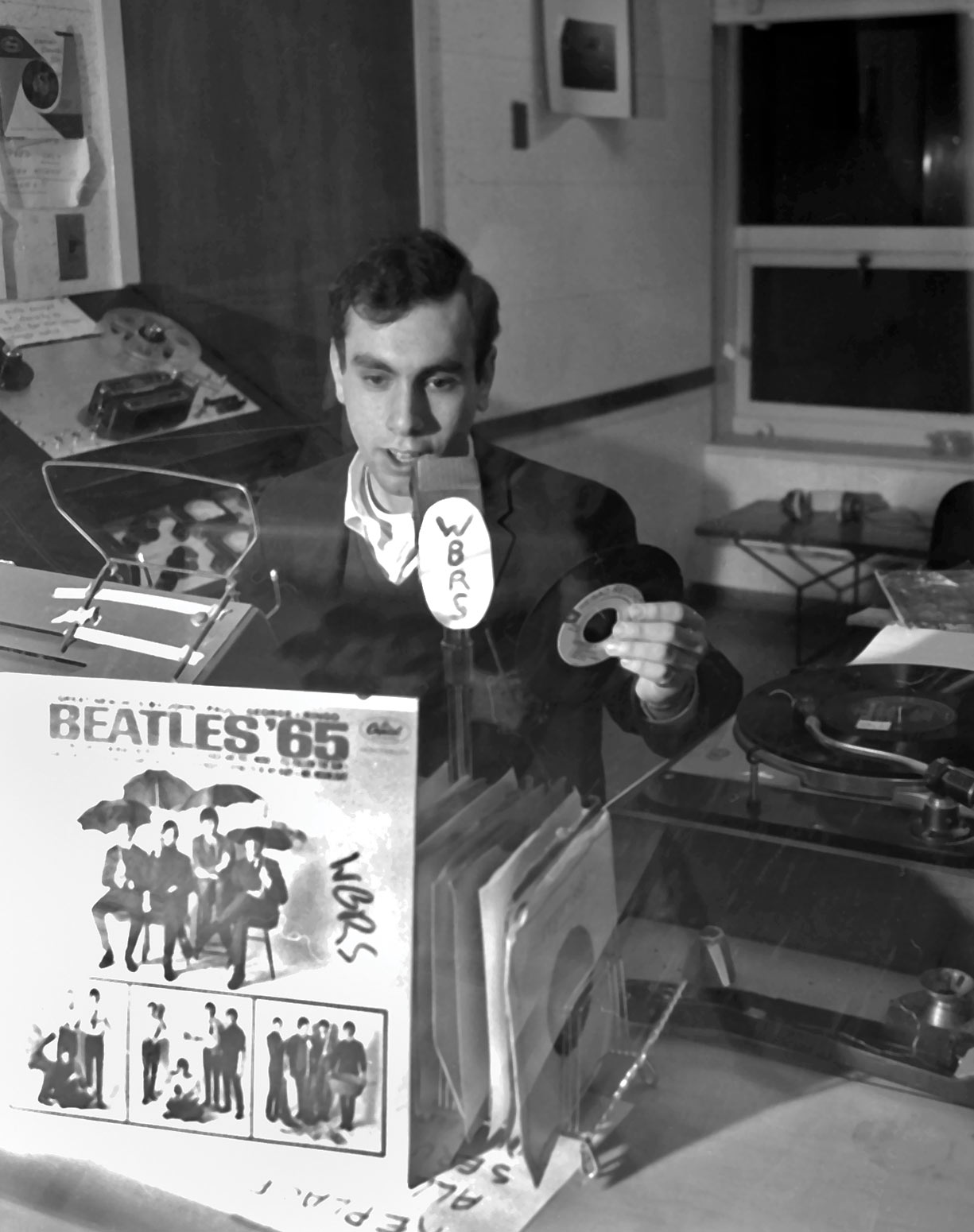Black and white photo of a radio host, a Beatles album is seen in the foreground