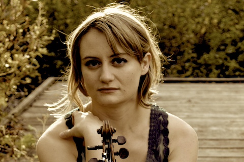 Sepia toned photo of white woman holding a violin to her chest