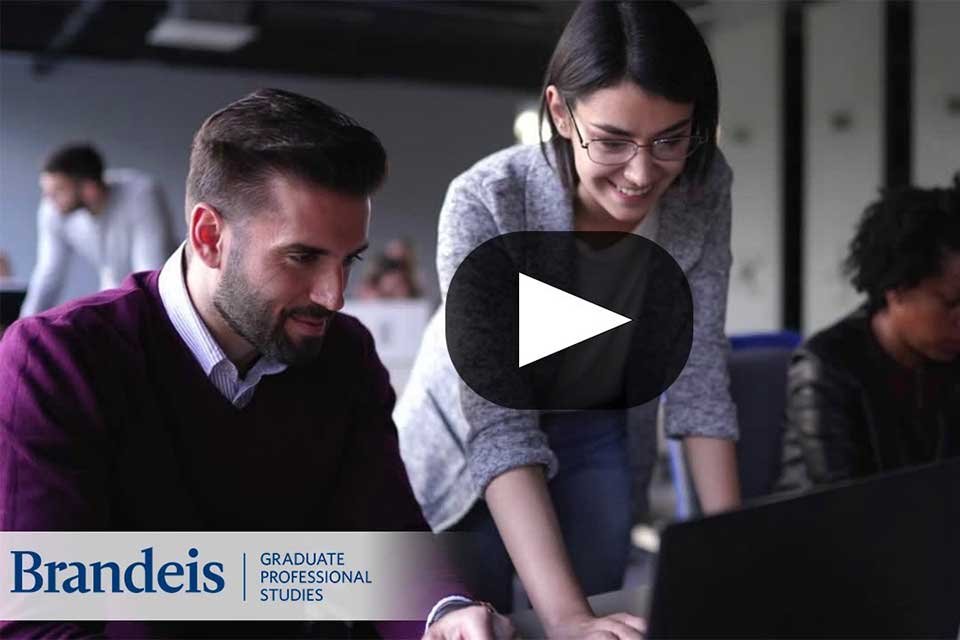 Two people talk while looking at a computer