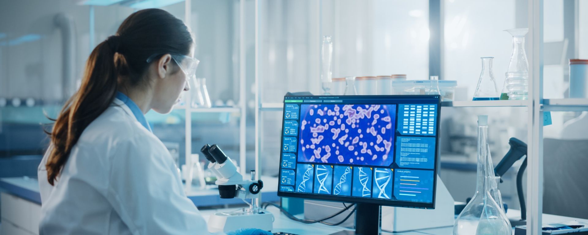 Person in a lab coat looks at a scan of cells on a screen