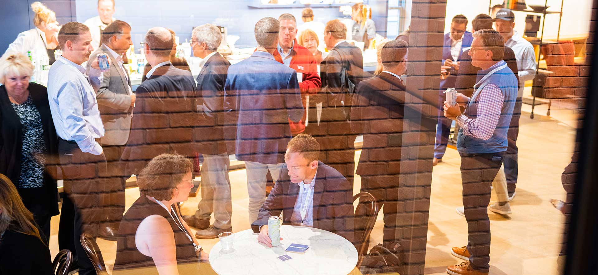 A room full of smiling happy adults dressed in nice suits meeting in an event room