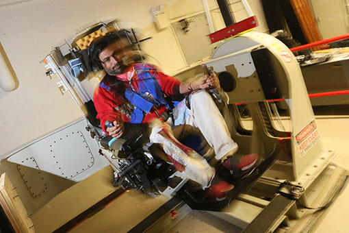 A Brandeis graduate student researcher sits in a motorized chair used to test how humans react to changes in motion and orientation in space.