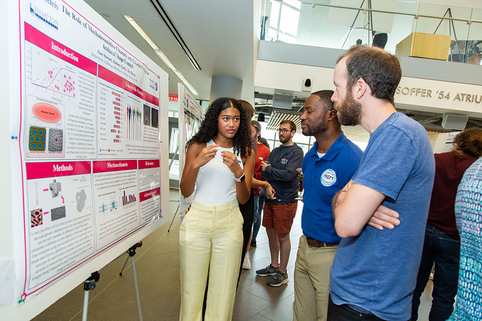 A student explaining their research poster.