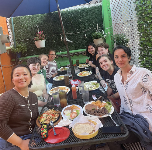 Fall 2024 PhD and Master's Cohort sitting on tables with Mexican food.