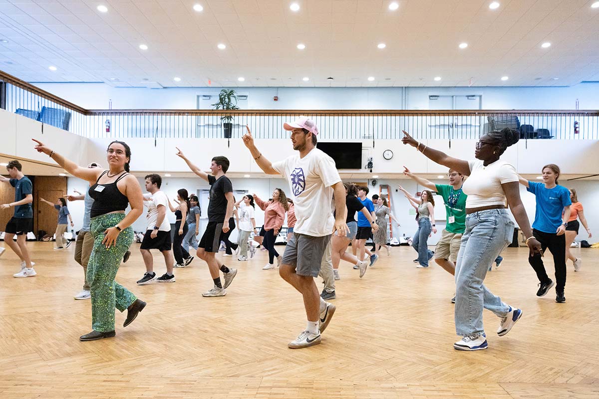 A large group of orientation leaders dancing and pointing