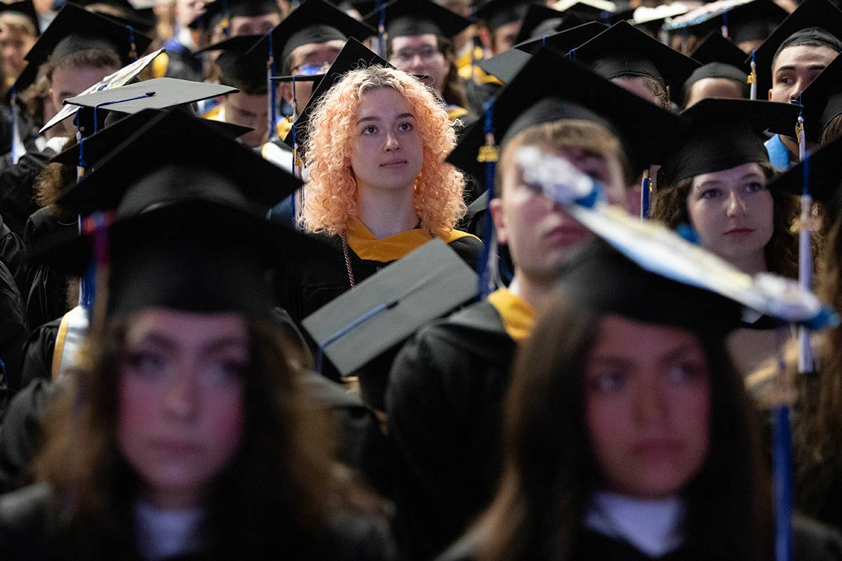 Graduates sit together during Commencement wearing their caps and gowns.